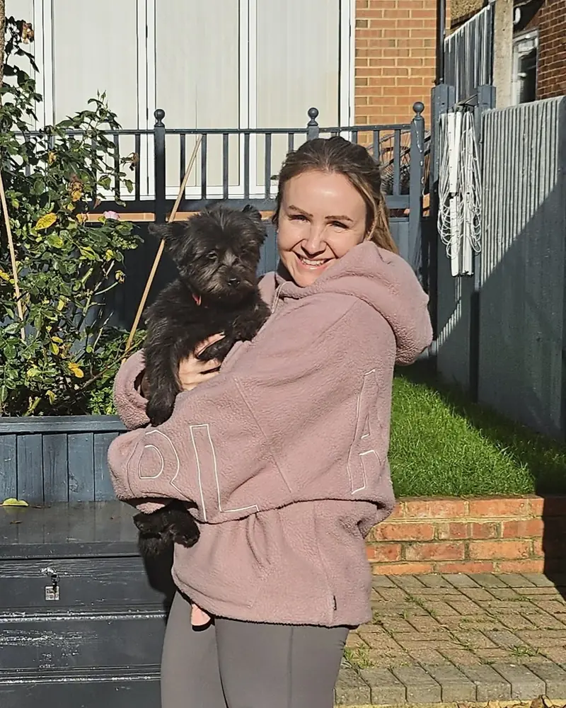 Lucy Goffin smiling, holding her small black dog